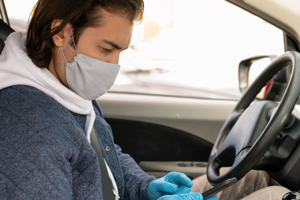 man with mask on in car